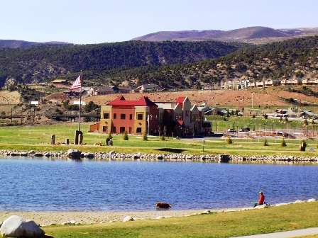 Lake in foreground with a red municipal building and mountains in the background.